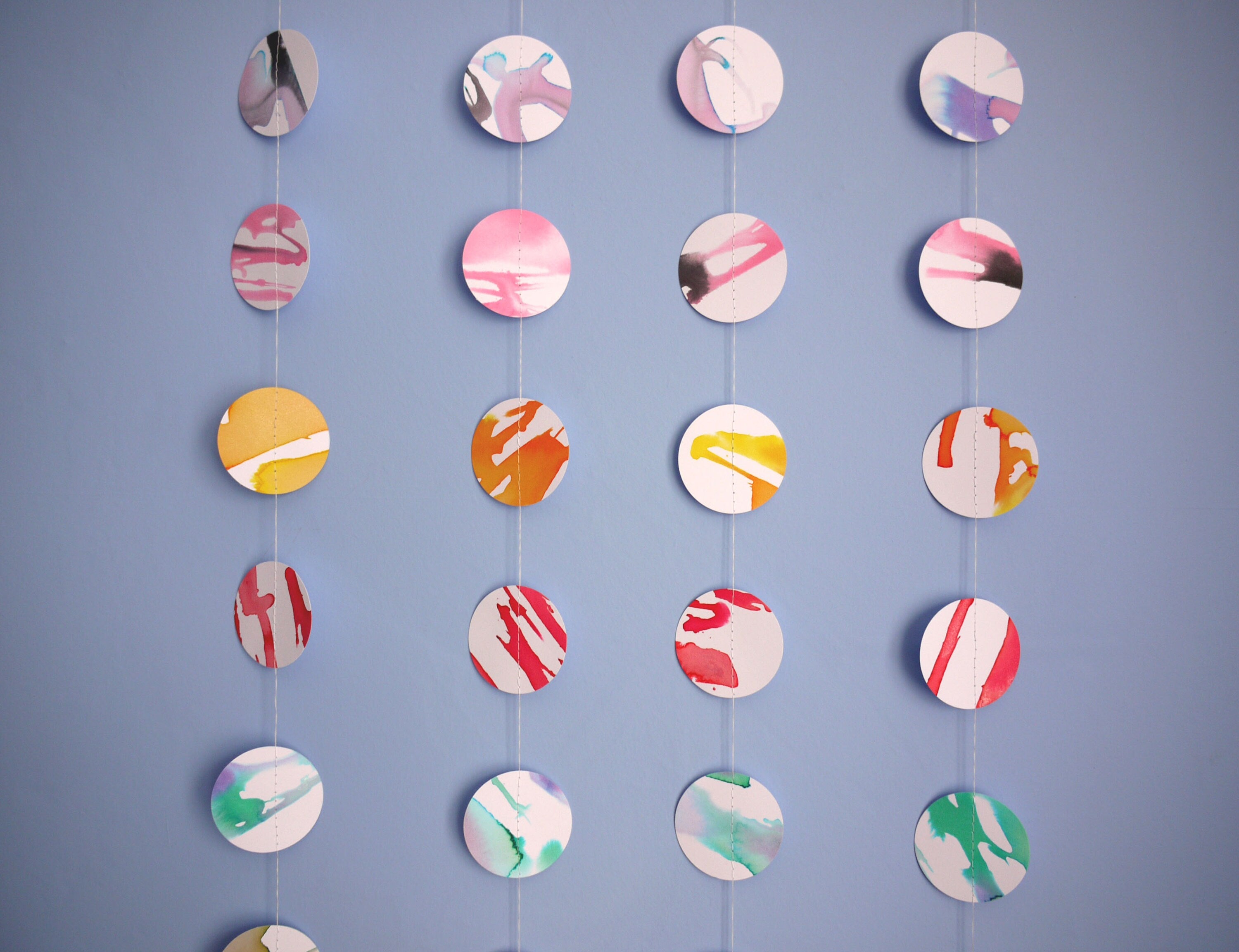 Close up on four colourful multicolour full moon paper garlands showing the unique look of each in comparison