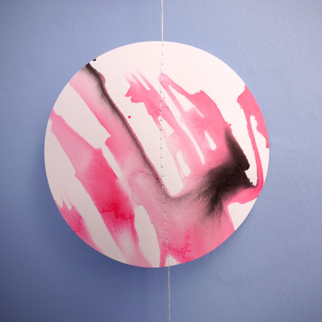 Close up of pink painted moon phase wall hanging on blue background 