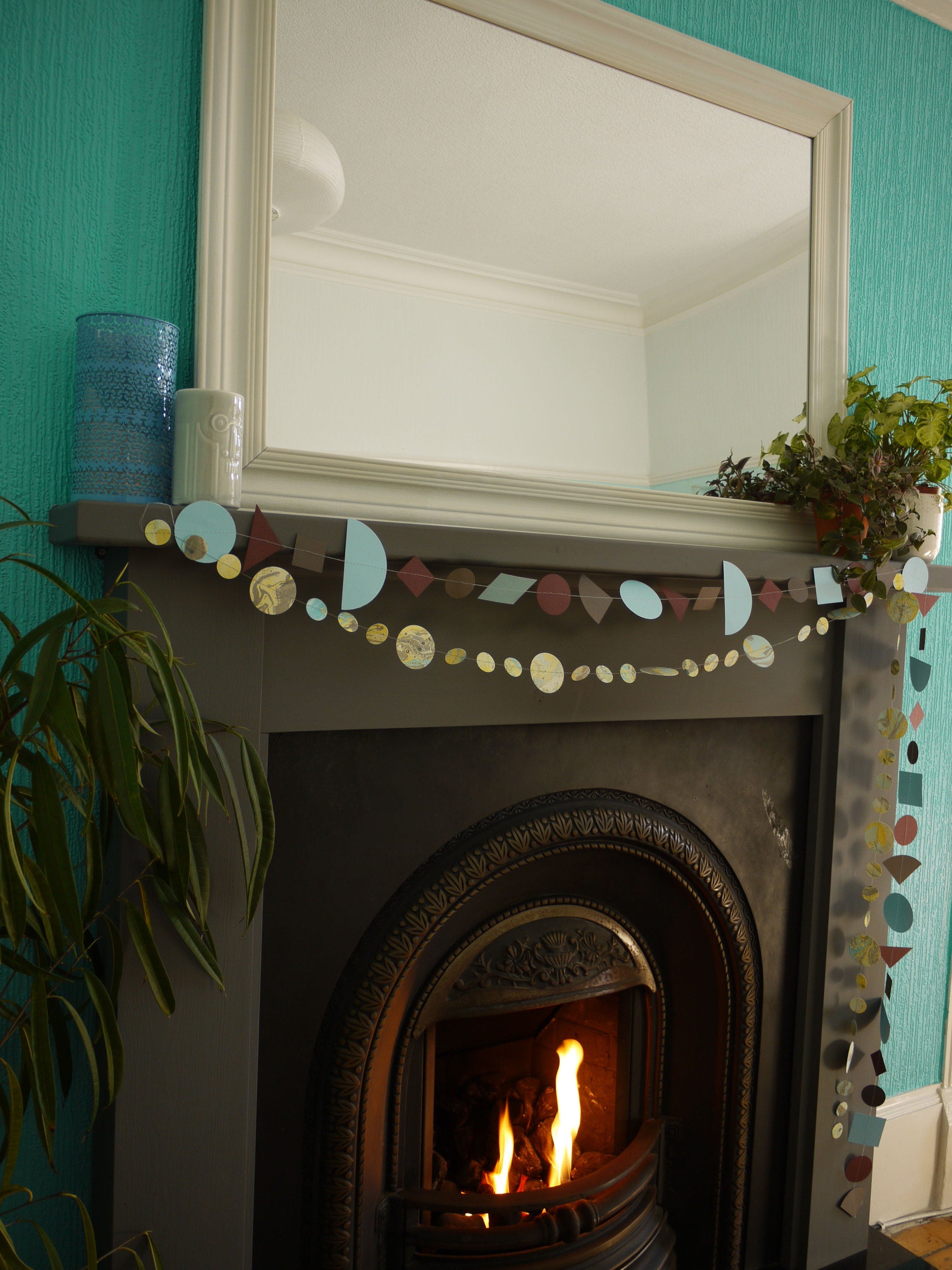 Paper garlands from Paper Street Dolls Ragnar collection. At a fireplace sits a multishape garland in cool tones, below a marbled circle garland 