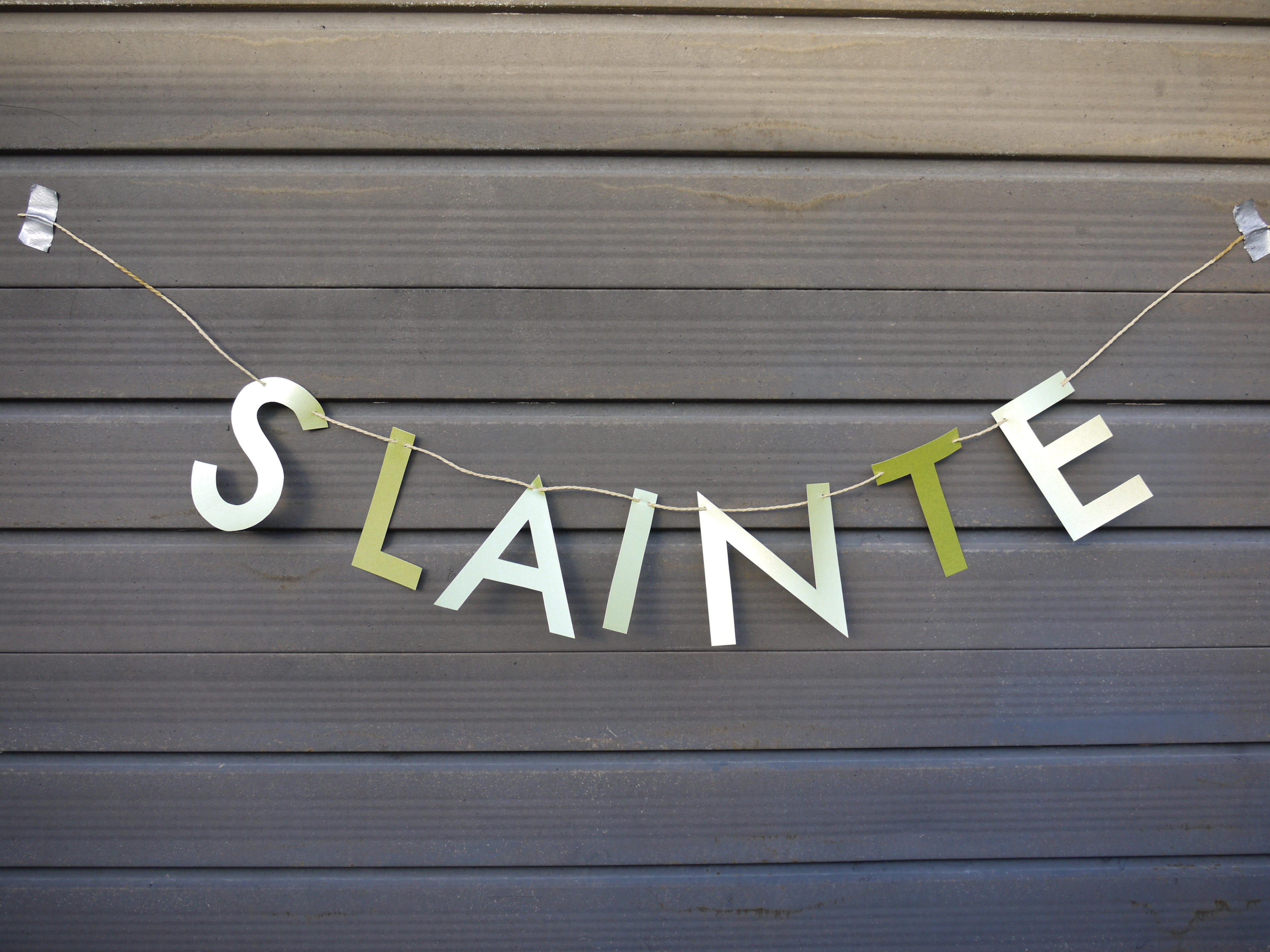 Bunting with 'SLAINTE' letters hanging against a wooden background