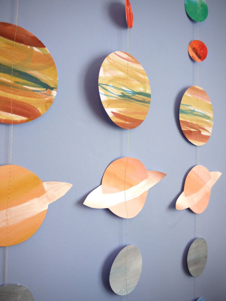 Colorful paper planet mobile hangings against a blue wall