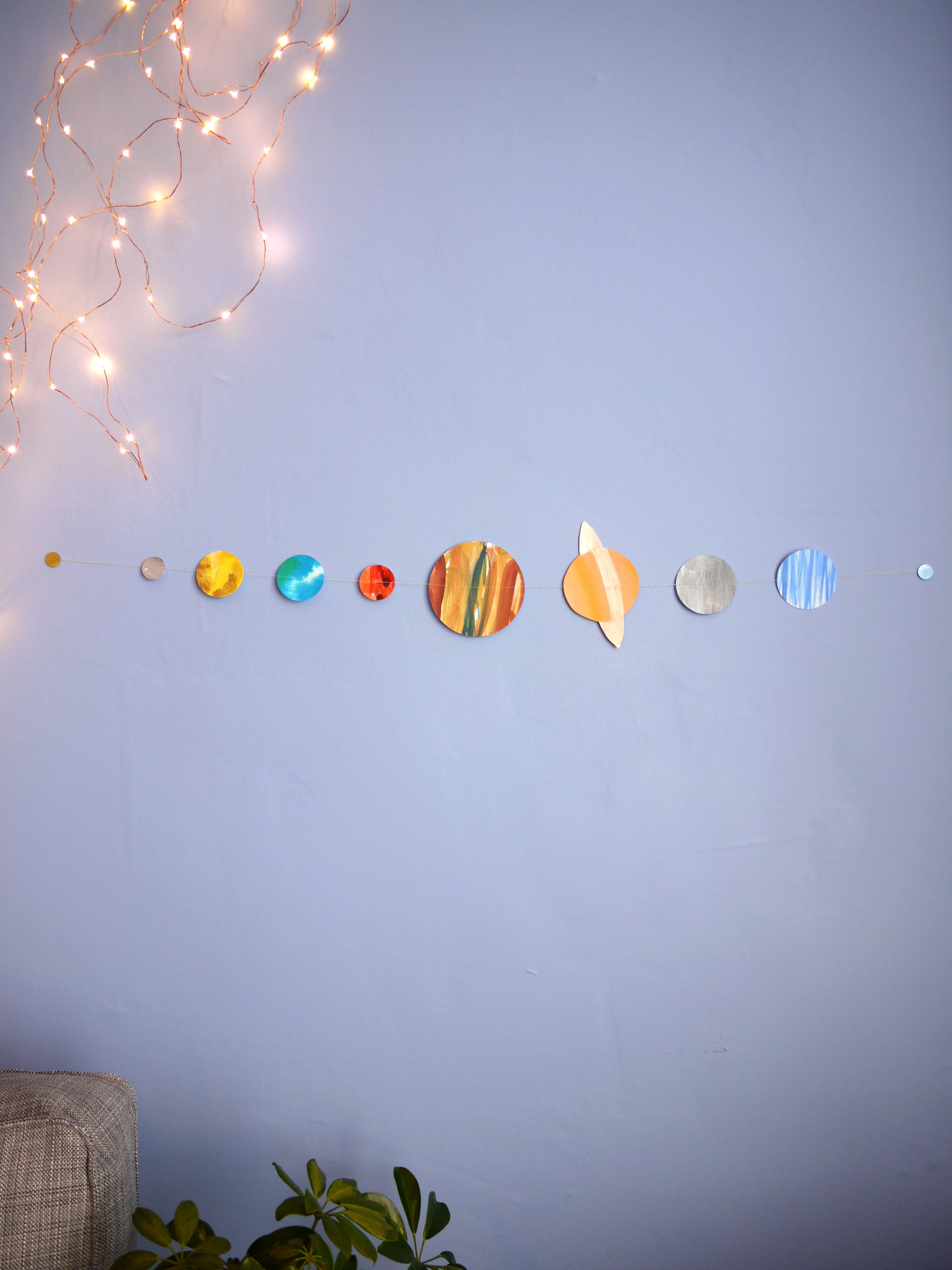 Colorful planet decorations on a wall with string lights