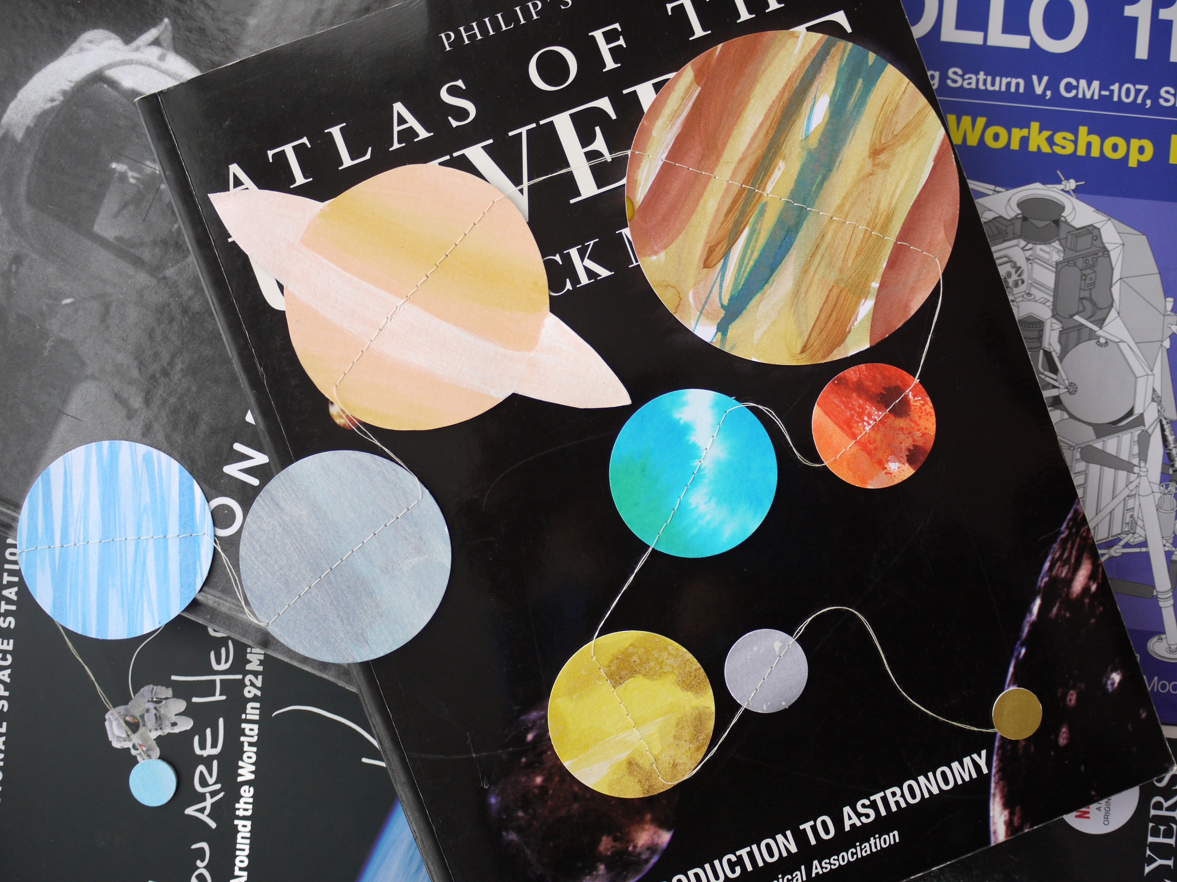 Book titled 'Atlas of the Universe' with colourful planet garland sitting on it.