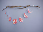 Pink and red moon phases paper garland hanging from driftwood on a blue wall