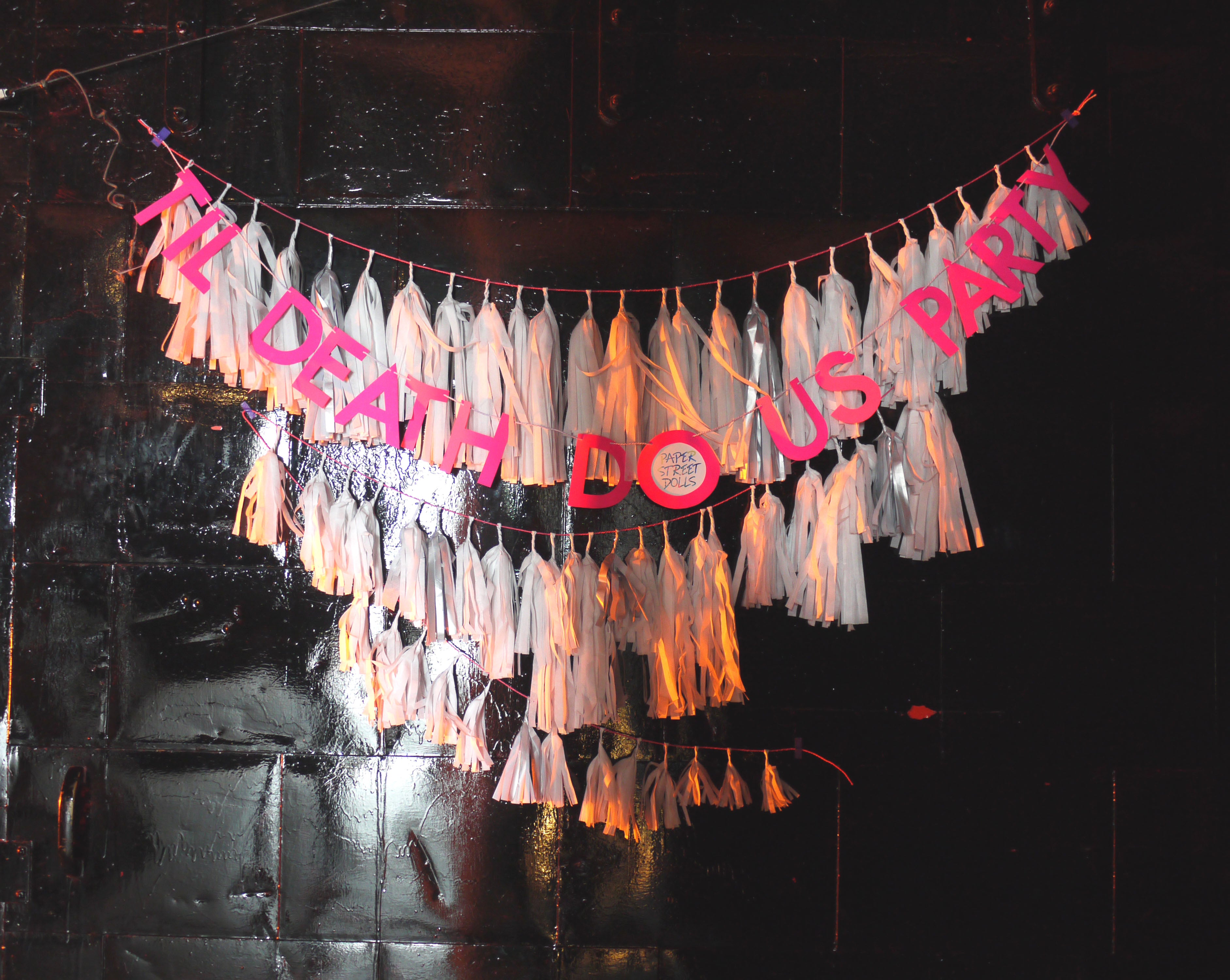 Decorative banner with 'TIL DEATH DO US PARTY' text and tassels on a dark background