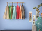 Soft coloured tassel wall hanging on a blue wall beside some Venice illustrations and trinkets