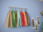 Soft coloured tassel wall hanging on a blue wall beside some Venice illustrations and trinkets