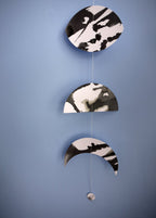 Black and white abstract moon wall hanging against a blue background