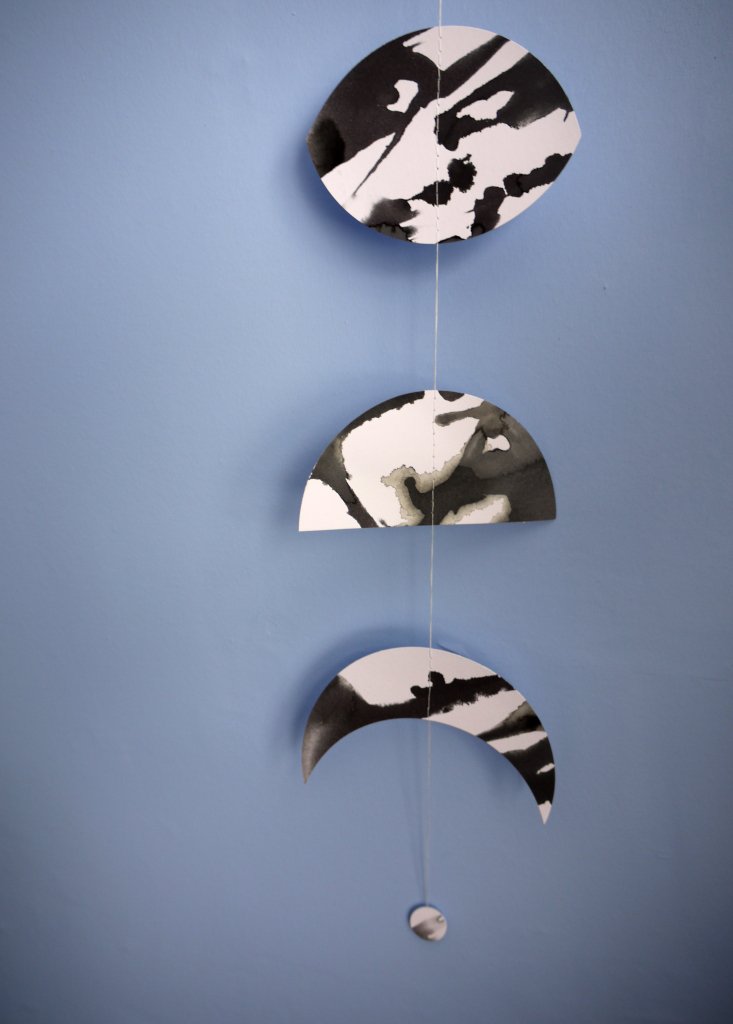 Black and white abstract moon wall hanging against a blue background