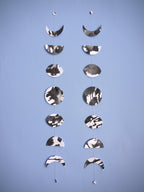 Decorative hanging mobile with moon phases on a blue background. Two paper garlands hang side by side for comparison of this unique handmade item