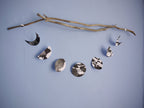 Decorative moon phases paper garland in black and white. Hanging horizontally from a branch and on a blue background