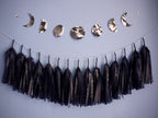 Decorative banner with moon phases and tassels on a blue wall