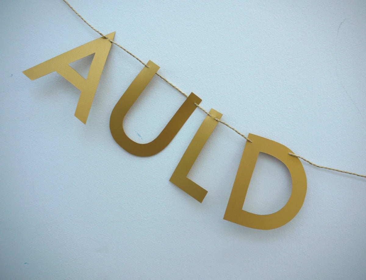 AULD of gold paper banner reads AULD LANG SYNE. Scots phrase decor as New Year at home idea.