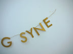SYNE of gold paper banner reads AULD LANG SYNE. Scots phrase decor as New Year at home idea.