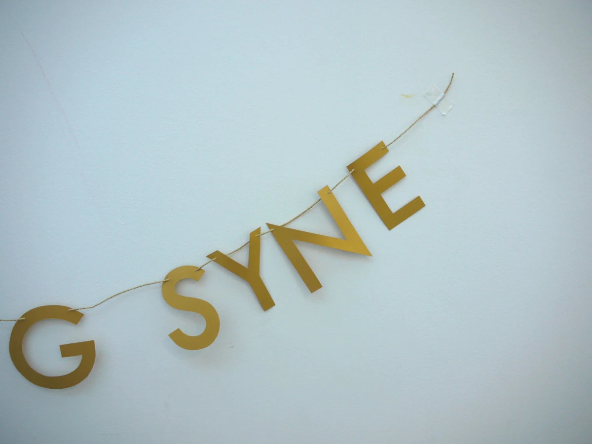 SYNE of gold paper banner reads AULD LANG SYNE. Scots phrase decor as New Year at home idea.