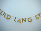 Gold paper banner reads AULD LANG SYNE. Scots phrase decor as New Year at home idea.
