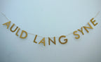 Gold paper banner reads AULD LANG SYNE. Scots phrase decor as New Year at home idea.