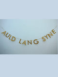Gold paper banner reads AULD LANG SYNE. Scots phrase decor as New Year at home idea.