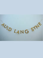 Gold paper banner reads AULD LANG SYNE. Scots phrase decor as New Year at home idea.