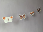 Four butterfly riso print shapes from a butterfly garland hanging on a wall as naturalist home decor.