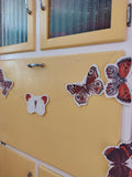 Yellow cabinet decorated with butterfly garland. Riso print shapes sewn for naturalist home decor.