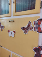 Yellow cabinet decorated with butterfly garland. Riso print shapes sewn for naturalist home decor.