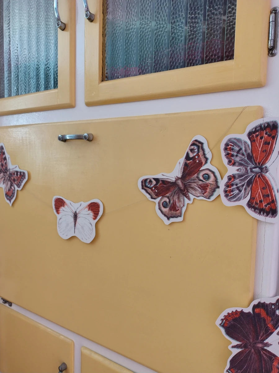 Yellow cabinet decorated with butterfly garland. Riso print shapes sewn for naturalist home decor.