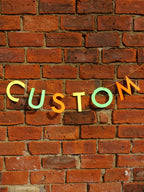 Colourful 'CUSTOM' letters on a brick wall