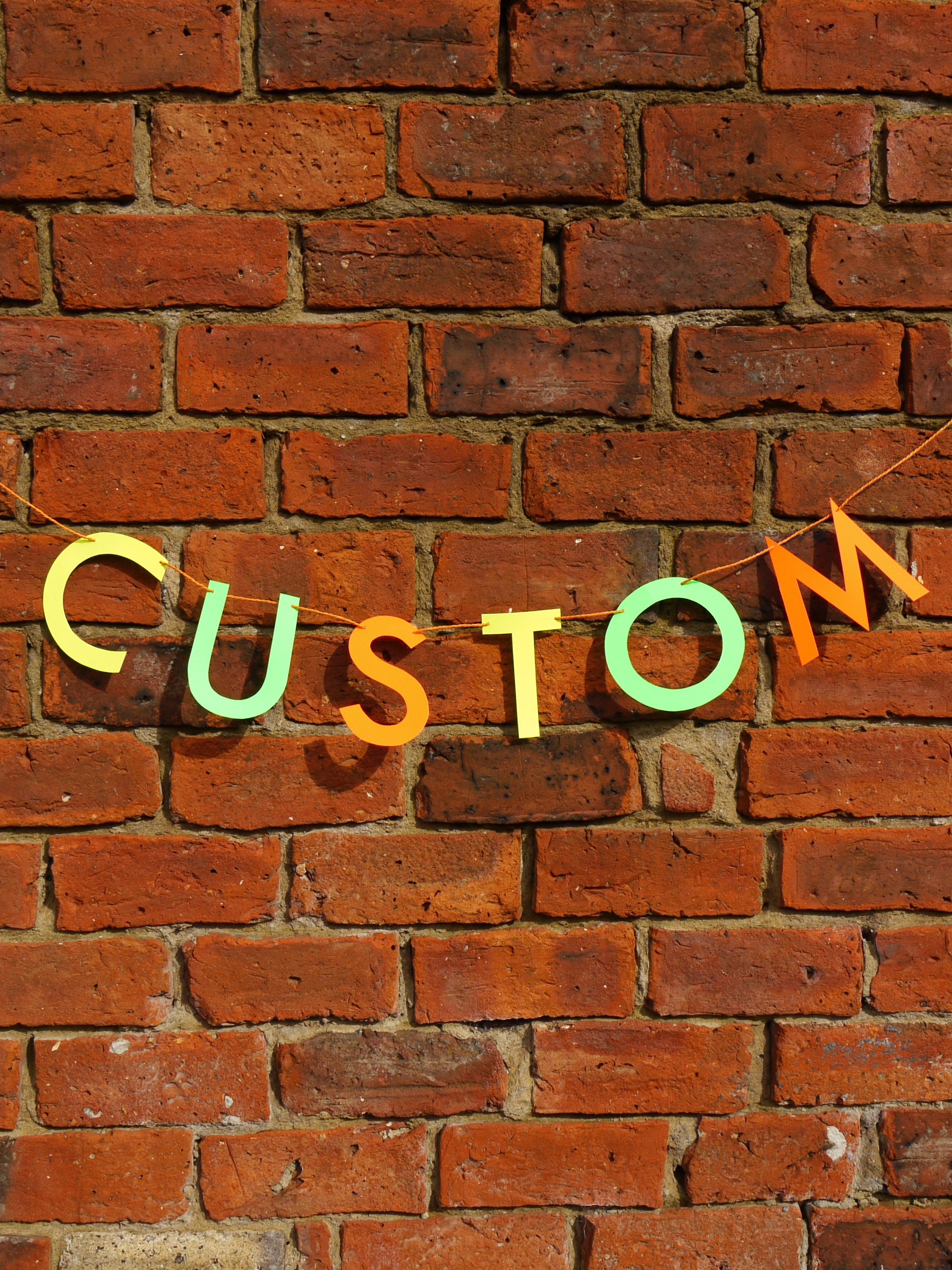 Colourful 'CUSTOM' letters on a brick wall