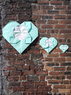Decorative origami heart shapes on a brick wall.