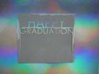 Holographic cake topper that reads 'HAPPY GRADUATION' for a graduation theme cake topper.