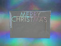 A 'Merry Christmas' cake topper with holographic card, set against a colourful holographic background.