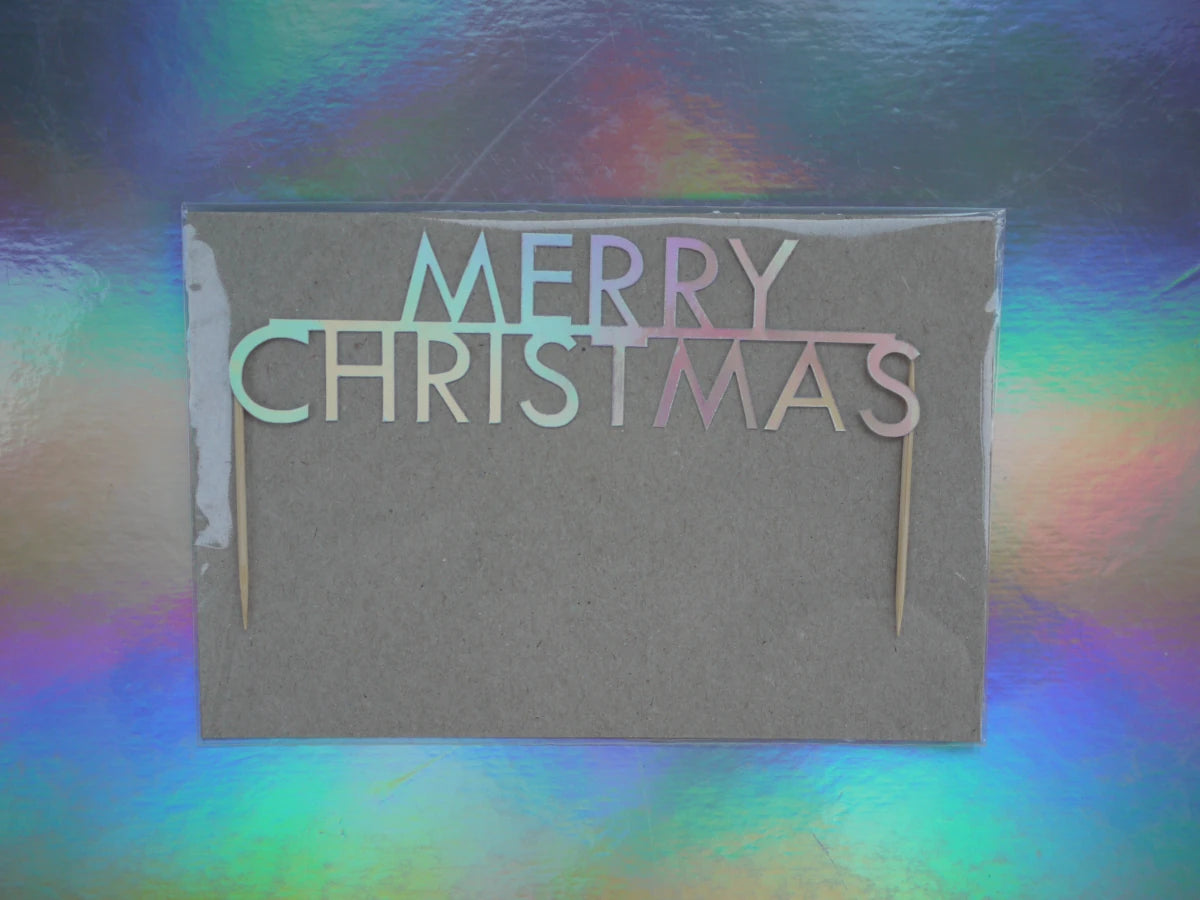 A 'Merry Christmas' cake topper with holographic card, set against a colourful holographic background.