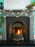 Easy New Year decorations of silver and gold circle paper garlands. A decorative fireplace scene with sewn paper garlands draped across the mantel.
