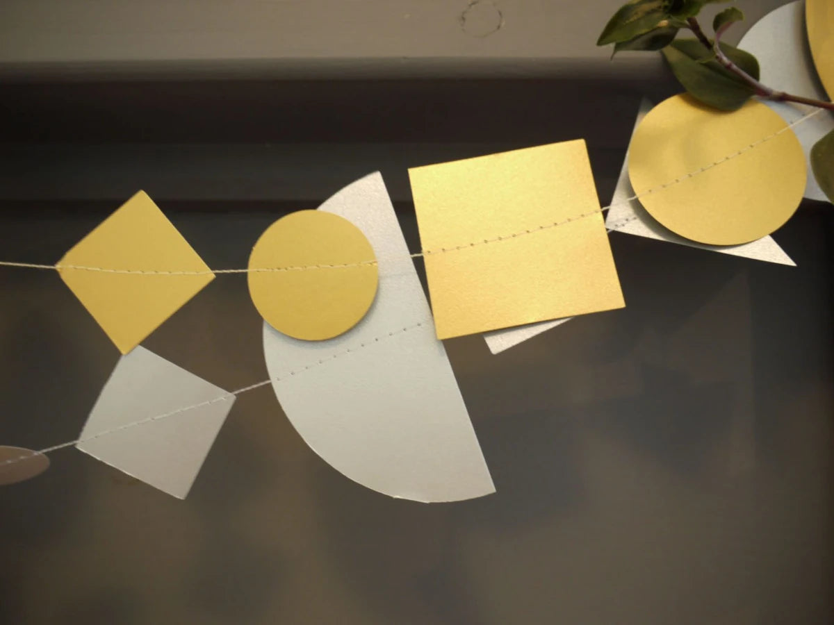 Metallic geometric sewn paper garlands with gold and silver shapes including circles, squares, and triangles. Fun easy party themes to take away the stress of decorating.