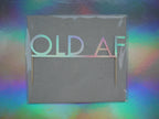 Holographic birthday cake topper with the phrase 'OLD AF' set against a holographic rainbow background.