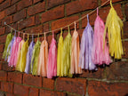 Pastel colourful tassel garland on a brick wall