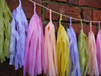 Close up on pastel colourful tassel garland on a brick wall