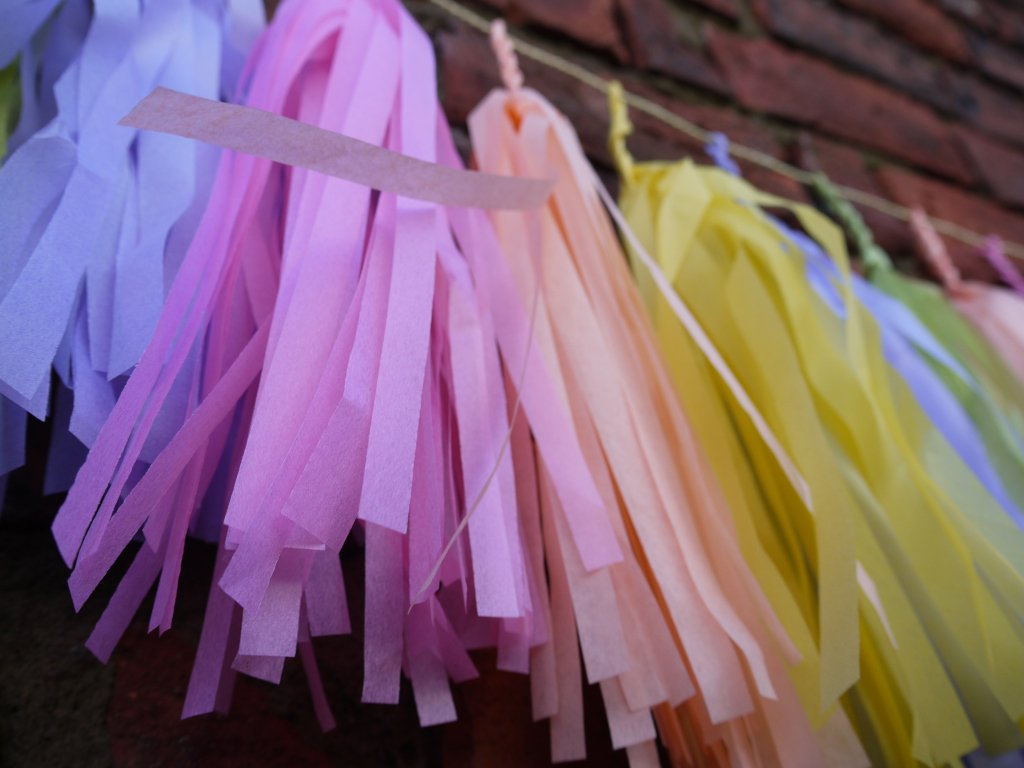 Close up pastel colourful tassel garland on a brick wall