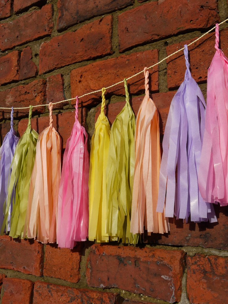 Pastel colourful tassel garland on a brick wall