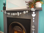 Decorative fireplace with geometric banner, plants, and mirror on a teal wall as part of fun easy party themes.