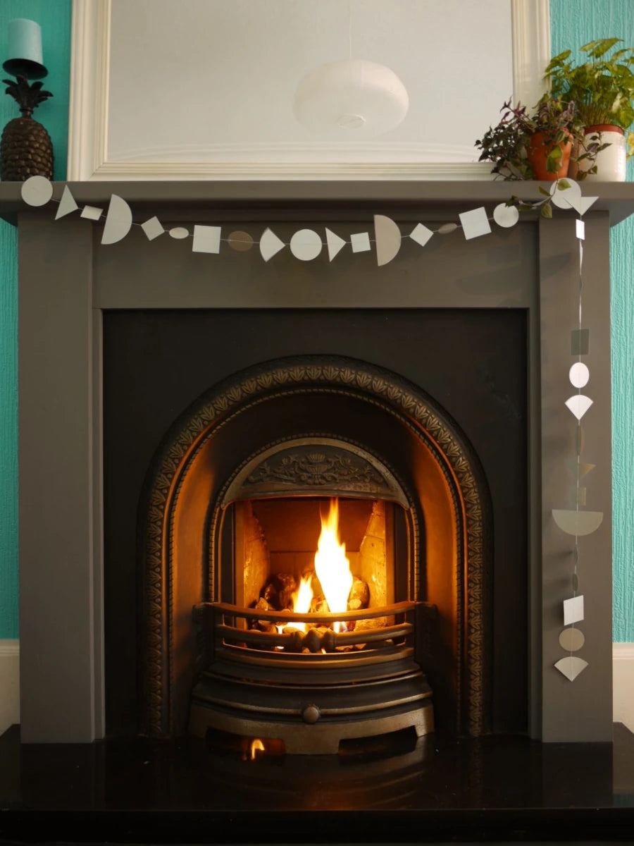 Silver multi shape paper garlands at a fireplace as part of fun aesy party themes.