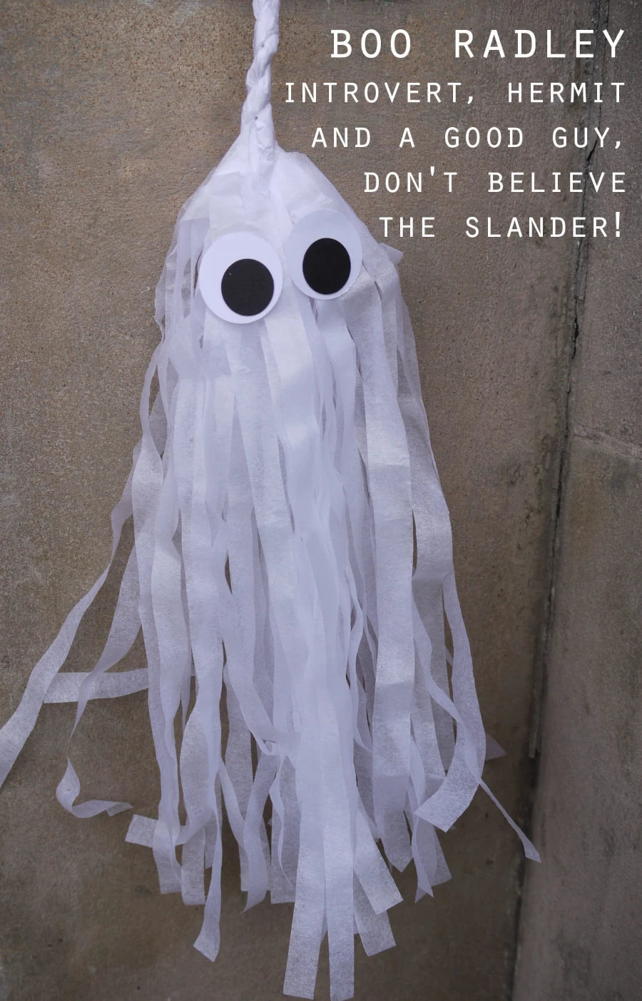 A white tissue paper ghost Halloween decoration with large eyes, spooky but cute, shown against a textured beige wall with white text reading 'BOO RADLEY INTROVERT, HERMIT AND A GOOD GUY, DON'T BELIEVE THE SLANDER!'.
